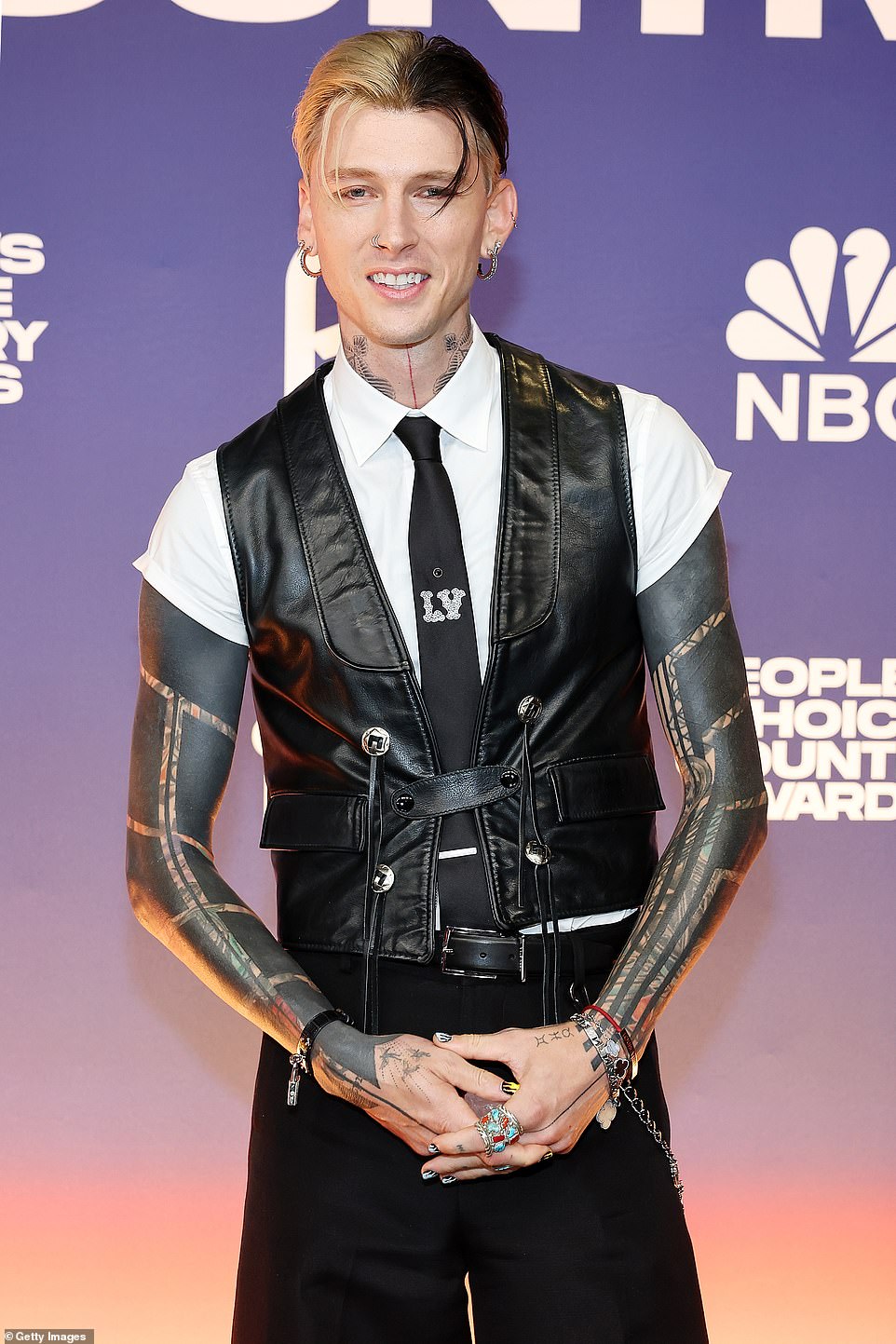 Rapper-turned-rocker Machine Gun Kelly showed off his edgy style in a lace-up leather vest, skinny Louis Vuitton tie and baggy black pants.