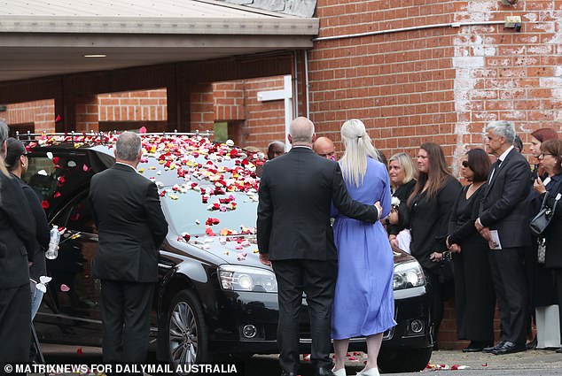 Mourners covered the hearse with petals before leaving for the cemetery after the funeral.