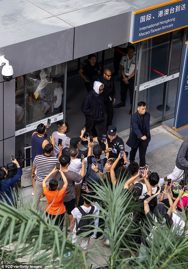 Completing the look with black sunglasses, Kanye was surrounded by his entourage as he left the airport after the flight to Haikou.