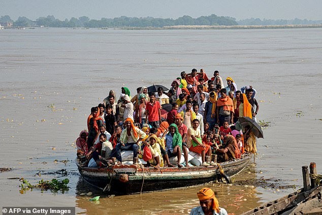 Flood-affected people, along with their belongings, move to a safer place in a boat after the water level of the Ganges river rises following heavy rains, in Patna on September 23.