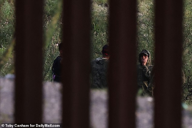 Camouflage-clad cartel smugglers wait for the perfect moment to sneak their human cargo across the U.S.-Mexico border in Arizona last month.