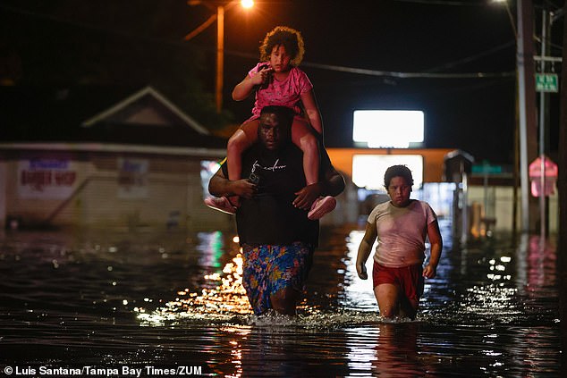 A family walks through floodwaters in Crystal River, Florida, early Friday.