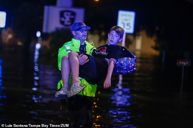 A Citrus County firefighter carries 11-year-old Michael Cribbins through floodwaters in Crystal River, Florida, Friday morning.