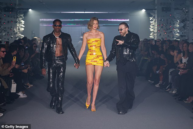 As the star show closed, Gigi appeared on the runway alongside Travis (left)