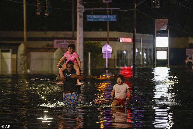 Jamir Lewis walks through floodwaters with his two daughters, Nylah and Aria, after Hurricane Helene on Friday.