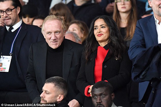 Salma looked stunning in a red knit sweater paired with pants and a long black trench coat, completing her look with a Gucci belt to cinch her waist.