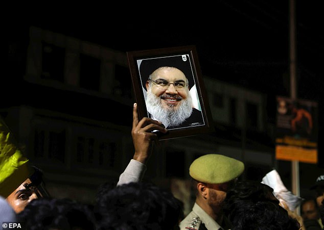 A Kashmiri Shia Muslim holds a photograph of late Hezbollah leader Hassan Nasrallah.