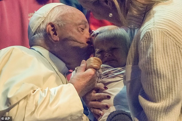 Pope Francis kisses a child during the Hope Happening youth festival at the Expo in Brussels, Belgium, yesterday