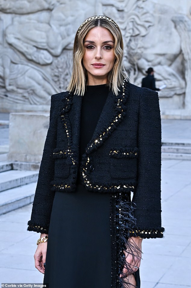 She modeled a stunning black woven jacket with gold trim and long skirts with a sexy slit and feathers.