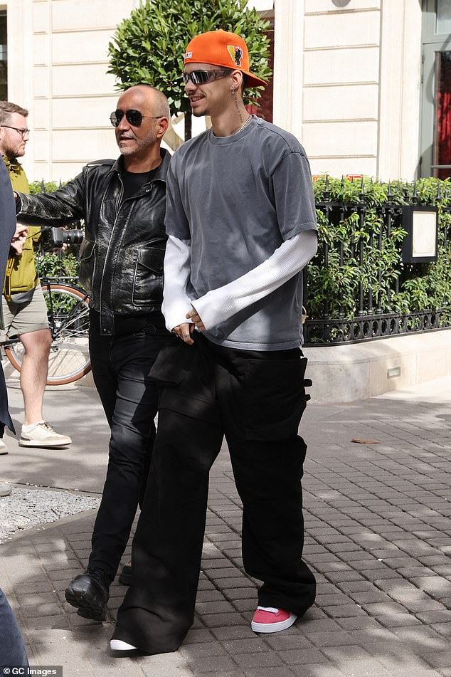 Romeo sported a white long-sleeved top paired with an oversized gray T-shirt, which he paired with loose-fitting black cargo pants and a pair of red Puma sneakers.