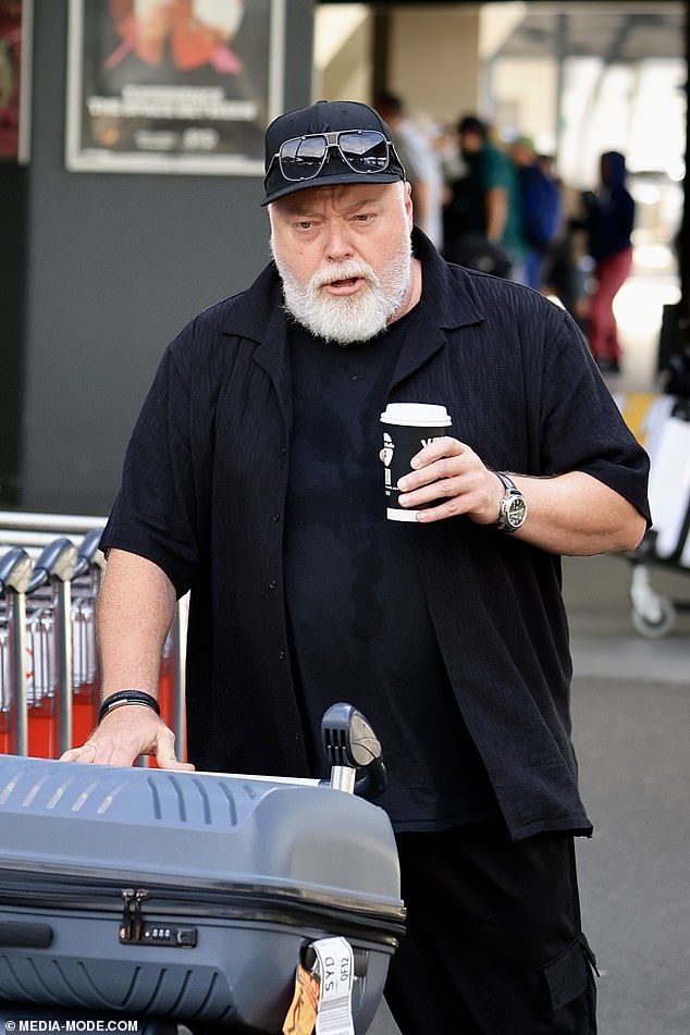 The radio king carried a cup of coffee in his hand as he pushed his family's luggage through the airport, balancing his sunglasses on top of his hat.