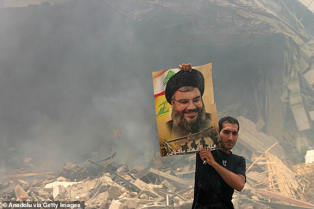 A Lebanese man shows a poster of Hezbollah leader Hassan Nasrallah, which he found in the rubble of his house in July 2006.