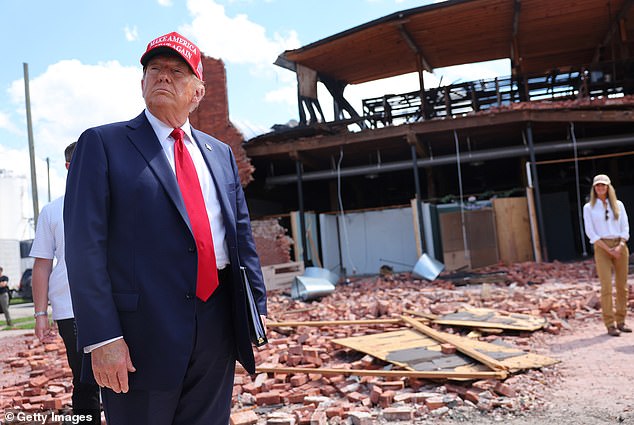 Republican presidential candidate former US President Donald Trump listens to a question while visiting the Chez What furniture store, which was damaged during Hurricane Helene.