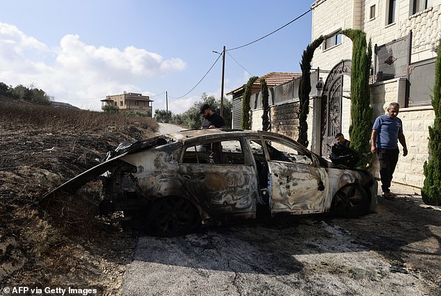 People check a burnt car a day after an attack by Jewish settlers in the village of Jit, near Nablus in the occupied West Bank, which left a 23-year-old man dead and others with serious gunshot wounds, on August 16, 2024.