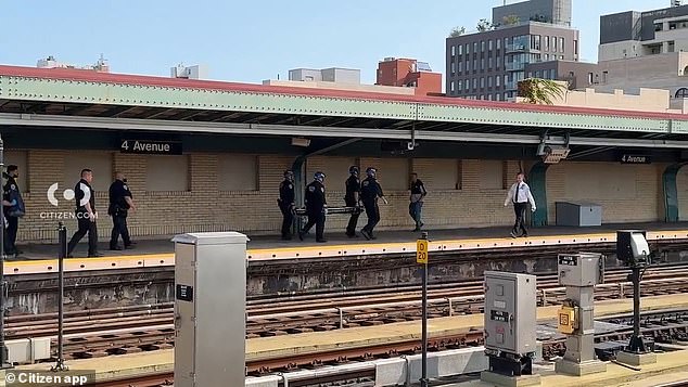 The horrific incident occurred near the 4th Avenue 9th Street station. (Pictured: Officers are seen carrying a covered stretcher onto the platform)