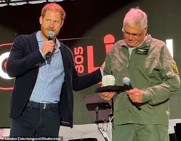 Prince Harry presents an award to helicopter pilot and lifeguard Loren Courtney on Saturday