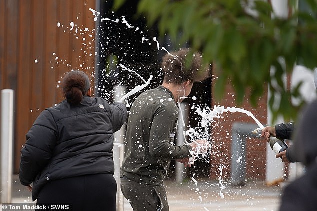 People spray a man with sparkling wine after he left HMP Nottingham prison following the government's controversial early release of prisoners