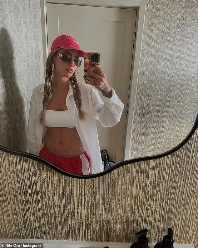 In another photo, Rita donned a strapless white top that showed off her six-pack and added an oversized white shirt and red and white sweatpants.