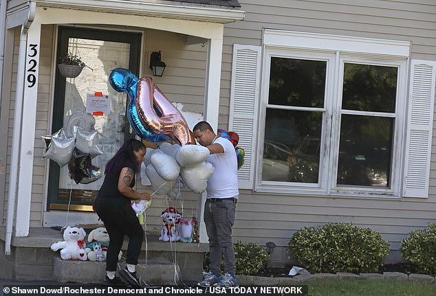 Irondequoit police said they discovered the bodies of two parents, a four-year-old girl and a two-year-old boy in a burned-out home in the early hours of Saturday. (Pictured: Mourners leave balloons outside the home on Knapp Avenue in Irondequoit)