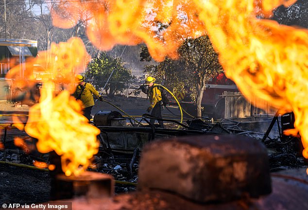 Firefighters work to extinguish numerous fire-ravaged homes as the Boyles Fire burns in Clearlake, California