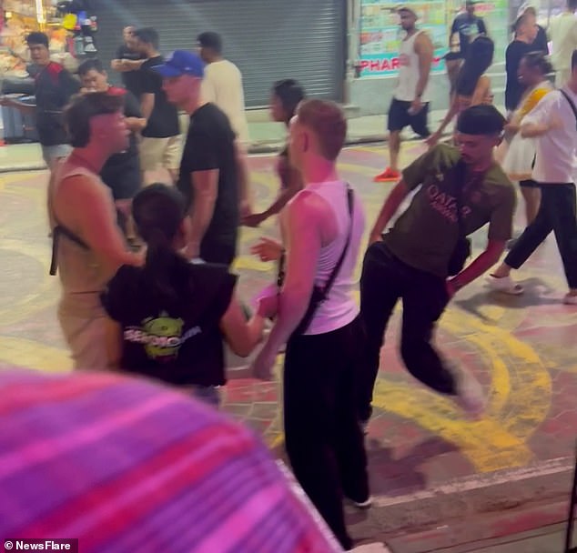 Locals and other tourists watched as one of the men pushed his partner (pictured) after becoming enraged by her 