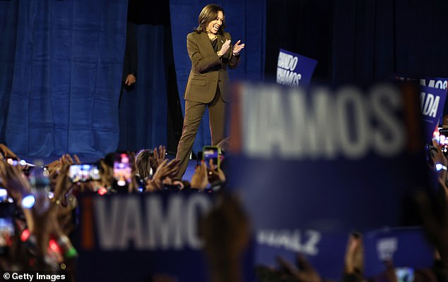 Democratic presidential candidate Vice President Kamala Harris takes the stage holding campaign signs that say 'Let's go!'