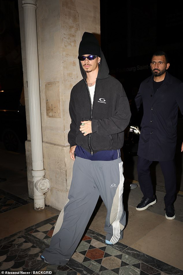 Romeo donned a pair of gray and white striped sweatpants over a pair of navy shorts for his outing.