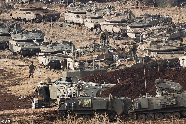 Israeli soldiers work on tanks in a staging area in northern Israel, near the Israel-Lebanon border, October 1, 2024.