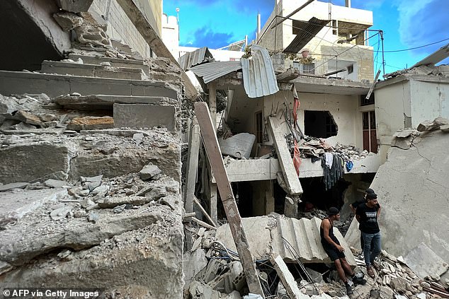 Residents inspect damage following an overnight Israeli airstrike on the Ain al-Helweh Palestinian refugee camp outside the southern port city of Sidon early on October 1, 2024.