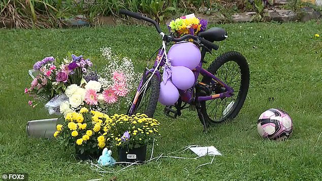 A memorial was installed in the family's front yard Monday with flowers, a soccer ball, stuffed animals and the girl's purple bicycle.