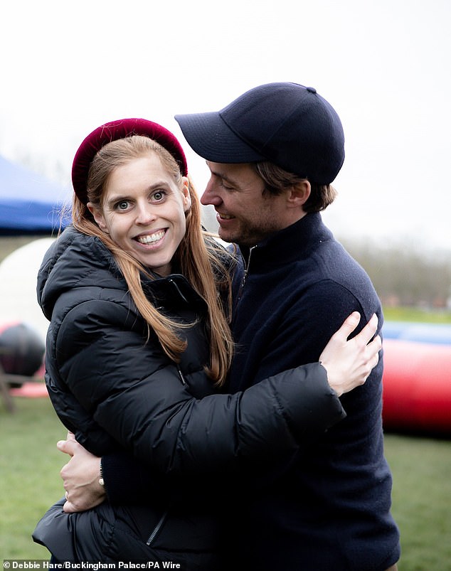 A new photograph published today of Princess Beatrice, dressed in a black down jacket, smiling at the camera, while being hugged by Edoardo Mapelli Mozzi, who looks at his wife.