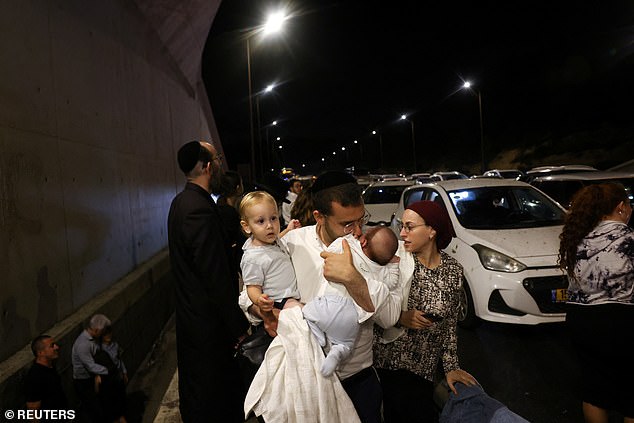 A man holds children as people take cover during an air raid siren, amid cross-border hostilities between Hezbollah and Israel, in central Israel on October 1.