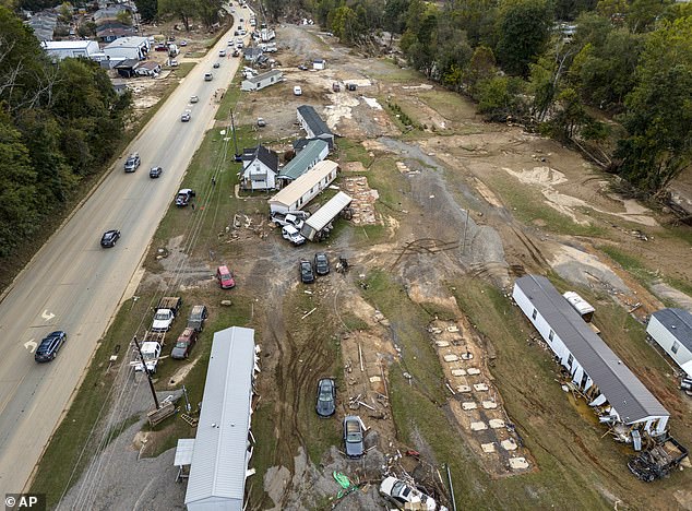 Homes and vehicles that were damaged by flash flooding caused by Hurricane Helene sit on the side of a road near the Swannanoa River in Swannanoa, North Carolina.