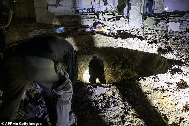 Israeli police inspect a crater left by a shell explosion in a heavily damaged school building in the southern Israeli town of Gedera.