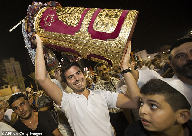 A Jewish man holds a Torah scroll during the Simhat Torah celebration in the Mediterranean coastal city of Netanya, north of Tel Aviv, on September 26, 2013.