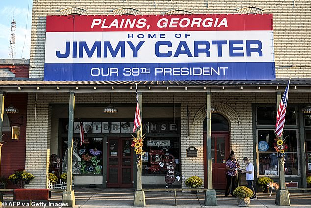 Gloria English (right), a local Plains resident and friend of former U.S. President Jimmy Carter, along with her caregiver Stacy Ludden, walk under a sign that reads 