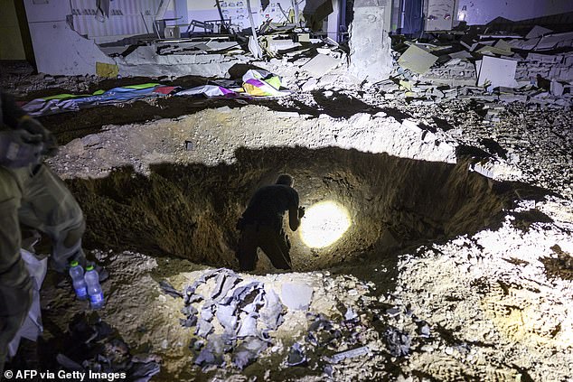 Members of Israel's Home Front Command and police forces inspect a crater left by a projectile that exploded in a heavily damaged school building in the southern Israeli town of Gedera on October 1, 2024.