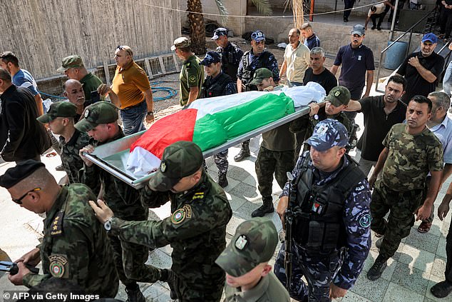 Members of the Palestinian National Security Forces carry the body wrapped in the Palestinian flag of Samer al-Asali, who was killed in Jericho by falling debris from one of the intercepted projectiles fired overnight by Iran at Israel.