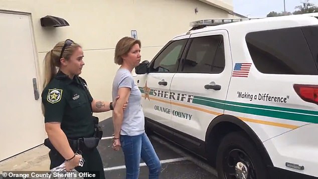 Boone is escorted by a police officer following her arrest in February 2020. Police discovered videos on her phone that allegedly showed the woman filming Torres pleading to be released from the suitcase.