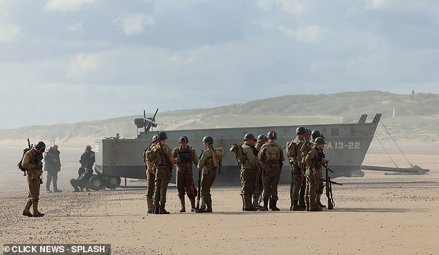 The actors, dressed in khaki uniforms and protective helmets, carried weapons and stormed the beach.