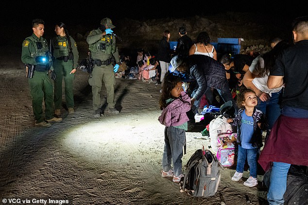 Migrants are processed by US Border Patrol agents after crossing into the US from Mexico via an abandoned railroad