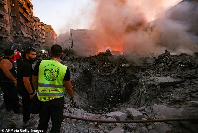 People and rescuers gather near the rubble of a building destroyed in the Israeli airstrike