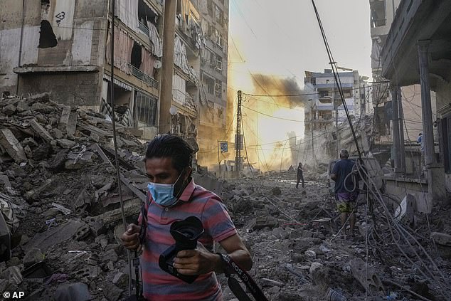 A photographer runs for cover as smoke rises in the background after an Israeli airstrike in Dahiyeh, Beirut, Lebanon, Friday, October 4, 2024.