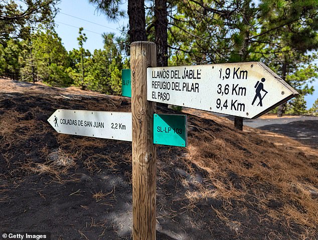 Above, a sign next to the Tajogaite volcano directs hikers to various landmarks. 