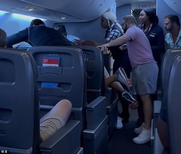 Passengers were seen shouting at him to take his hands off the woman sitting next to him while a flight attendant tried to mediate.