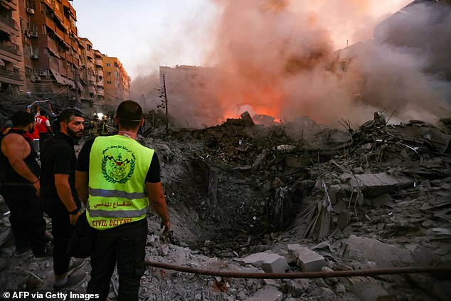 People and rescuers gather near the rubble of a building destroyed in the Israeli airstrike