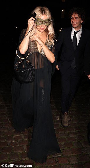 Sienna Miller opted for a transparent flowy dress with a gold mask