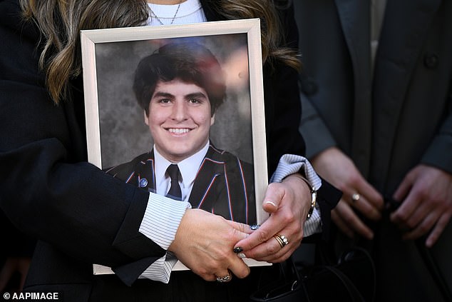 A portrait of James Tsindos is held as Shari Liby, legal counsel for Slater and Gordon Medical Law, speaks to the media during the inquest into the death.