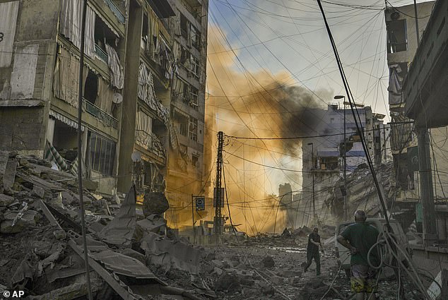 A man runs for cover as smoke rises in the background after an Israeli airstrike in Dahiyeh, Beirut, Lebanon, Friday, October 4, 2024.