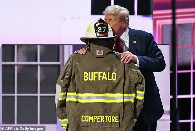 Former US President and 2024 Republican presidential candidate Donald Trump kisses a firefighter's helmet and jacket that belonged to Corey Comperatore